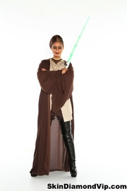 Gorgeous hottie posing in a light and chocolate brown jedi knight costume and black boots while holding a green light saber.