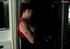 Hot redhead wearing red and black dress looks outside the window with