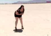 Big fat babe pops her monstrous juggs out of her black dress while she lets her pussy peek in a desert.