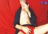 Old dude lays down and smokes a cigarette on a red bed wearing a black