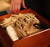 Naked brunette on a black table gets pinched with several clothespins.
