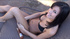 Awesome fawn in a black bikini shows her assets on a grey lounge chair.