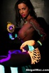 Siren in a mesh tube dress plays with toys under black light.