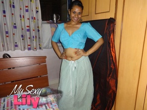 Luscious Indian hottie displays her chubby body before she opens her hanging blue blouse and reveals her big soft breasts then pulls down her white skirt and expose her huge juicy butt in her bedroom. - Picture 1