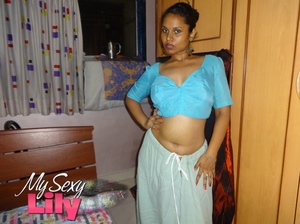 Luscious Indian hottie displays her chubby body before she opens her hanging blue blouse and reveals her big soft breasts then pulls down her white skirt and expose her huge juicy butt in her bedroom. - Picture 2