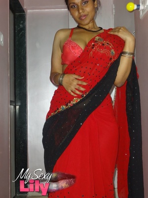 Stunning Indian chick displays her hot curves in red and black dress before she pulls it down and bares her hot tits with big nipples under her red bra on a gray and white bed. - Picture 2
