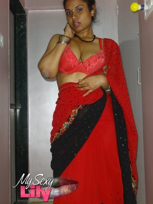 Stunning Indian chick displays her hot curves in red and black dress before she pulls it down and bares her hot tits with big nipples under her red bra on a gray and white bed. - Picture 4
