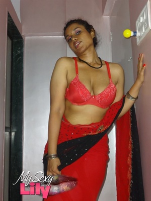 Stunning Indian chick displays her hot curves in red and black dress before she pulls it down and bares her hot tits with big nipples under her red bra on a gray and white bed. - Picture 5