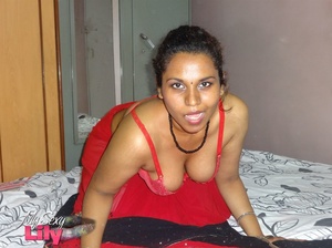 Stunning Indian chick displays her hot curves in red and black dress before she pulls it down and bares her hot tits with big nipples under her red bra on a gray and white bed. - Picture 11