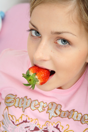 Gorgeous teen in pink shirt, skirt and socks loves to tease as she seductively eats her strawberries before she takes off her top and expose her juicy tits on a pink hearted bed. - XXXonXXX - Pic 1