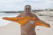 Naughty granny displays her fat round body on a beach wearing her orange nighty then takes it off and bares her big breasts and ravishing pussy.