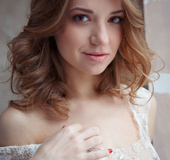 Superb bird in her sheer white lingerie sits on a brown leather chair.