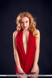 Charming gurl takes off her red dress in front of a blue background.