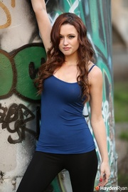Brunette chick displays her lusty body wearing her blue shirt by a grafitti wall before she pulls down her black leggings and expose her hot butt wearing her black thong.