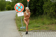 Raunchy vamp in black sneakers hitchhiking in her birthday suit.