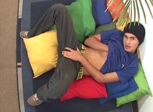 Sensational twink in a blue shirt and brown pants jerks off on some pillows. - Picture 1