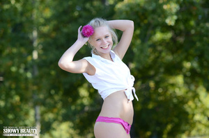 Banging teen blonde strips off her hanging white shirt then pose her foxy body in pink bikini before she takes them off piece by piece and expose her small tits and juicy pussy on a brown wooden bench in a beach. - Picture 3
