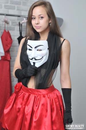 Teen brunette takes off her white mask then shows her beautiful face before she slowly peels off her black and red dress then displays her big juggs as she pose topless before she takes down her black thong and teases with her sweet twat as she spreads her legs wide while she sits on a red chair wearing her black gloves. - Picture 2