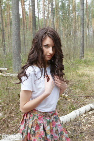Lovely brunette goes in the woods then peels off her white shirt and shows her sweet boobs before she opens her legs wide and bares her indulging pussy as she strips off her multi-colored skirt while she sits on a bamboo bench. - XXXonXXX - Pic 1