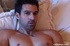 Muscular dude lays on a white bed and displays his huge hard body before