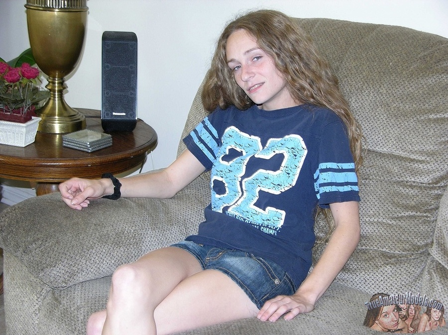 Teen babe with skinny body sits on a gray couch then peels down her jeans skirt and yellow panty and shows her hairy pussy on a gray couch before she takes off her blue shirt and reveals her small tits as she sits naked on a black chair wearing her white rubber shoes. - XXXonXXX - Pic 1