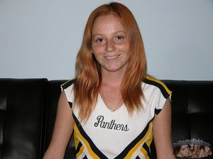 Skinny cheerleader takes off her black panty and displays her nasty pussy under her black, white and yellow uniform before she gets naked and expose her small tits on a multi-colored striped bed. - Picture 2