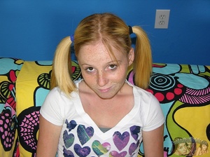 Teen blonde in pigtails sits on a multi-colored couch then takes off her white with vari-colored hearts shirt and gray bra and shows her tiny boobs before she peels down her jeans and reveals her lusty crack on a black and white bed. - Picture 3
