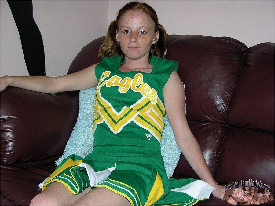 Teen cheerleader in pigtails peels down her pink and blue panty and expose her sweet pussy in different poses on a green seat wearing her green and yellow uniform before she takes it off and lays naked on a violet and white bed. - XXXonXXX - Pic 1
