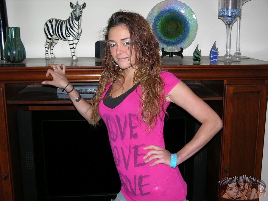Curly redhead takes off her pink shirt then displays her banging body before she peels off her red and black bra and reveals her juicy tits then strips down her jeans and black panty and seduces with her alluring pussy in different positions on a gray couch, brown chair and bed. - XXXonXXX - Pic 1