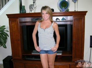 Blonde bombshell displays her stunning body wearing her gray and white striped shirt, jeans shorts, white bra and green panty and reveals her indulging pussy and luscious boobs as she slowly gets naked while she pose on a gray couch, in a kitchen and on a black bed. - Picture 1