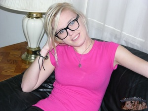 Pretty blonde with glasses takes off her pink shirt and black and blue bra then seduces with her small tits and slim body as she lays topless on a black couch before she peels down her black pants and expose her lusty crack as she opens her legs wide on a blue and white bed. - XXXonXXX - Pic 2