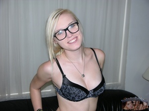 Pretty blonde with glasses takes off her pink shirt and black and blue bra then seduces with her small tits and slim body as she lays topless on a black couch before she peels down her black pants and expose her lusty crack as she opens her legs wide on a blue and white bed. - Picture 3