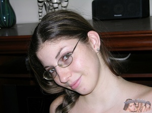 Pretty babe in ponytail wearing glasses shows her lusty pussy as she opens her legs wide on a gray couch before she strips off her white, brown and gray tube top and jeans skirt and expose her skinny body with tiny tits in a kitchen and on a gray bed. - XXXonXXX - Pic 1