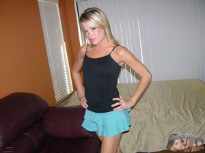 Banging blonde lays on a brown couch and teases with her banging body wearing her sexy black shirt and turquoise skirt before she peels them off and expose her tiny boobs and shaved pussy in different poses. - Picture 3