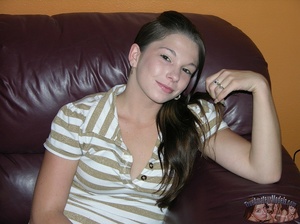 Teen chick sits on a brown couch then strips off her gray and white striped shirtand shows her lusty boobs before she peels down her white skirt and reveals her indulging pussy on a gray and white bed. - XXXonXXX - Pic 2