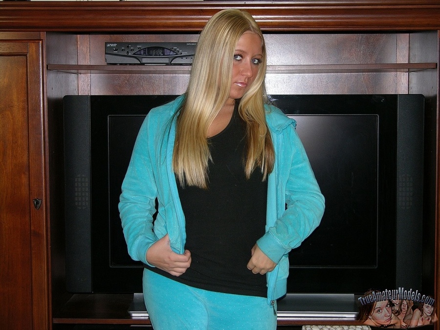 Blonde bombshell seduces as she slowly strips off her turquoise jacket and jogging pants and displays her big ass then takes off her black shirt and expose her huge juggs and indulging pussy in different poses on a gray couch, wooden chair and white bed. - XXXonXXX - Pic 2