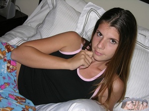 Teen hottie pose her slim body as she lays on a white bed then peels down her multi-colored pajama pants and reveals her hairy pussy before she takes off her black shirt and expose her tiny tits and huge ass in different poses. - Picture 1