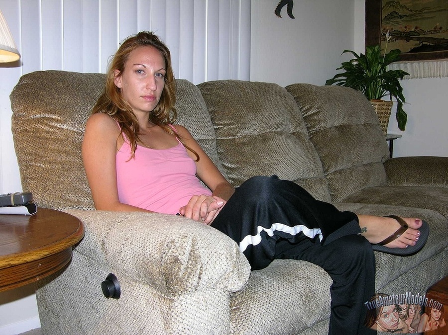 Beautiful babe sits and lays on a gray couch and teases with her steaming hot body before she peels off her pink shirt, black jogging pants and thong then reveals her tiny tits and ravishing pussy on a gray couch and red bed before she holds a hard cock then wanks it on a pink and blue floral couch. - XXXonXXX - Pic 2