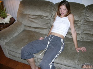 Smoking hot brunette sits on a gray couch and pose her skinny body before she takes off her white shirt and shows her small tits then pulls down her gray jogging pants and expose her hairy crack on a white bed before she sucks a bald dude's dick on a black chair then lets him fuck her on a blue bed. - XXXonXXX - Pic 2