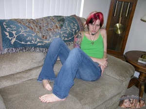 Young babe with red hair and tattoos lays down on a gray couch then pulls down her jeans and blue panty and reveals her alluring pussy before she takes off her green shirt and shows her tiny tits as she lays down naked on a gray bed. - XXXonXXX - Pic 2