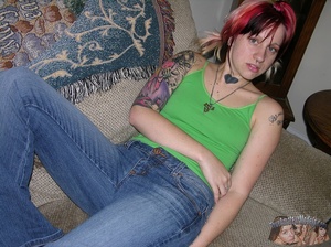 Young babe with red hair and tattoos lays down on a gray couch then pulls down her jeans and blue panty and reveals her alluring pussy before she takes off her green shirt and shows her tiny tits as she lays down naked on a gray bed. - XXXonXXX - Pic 3