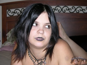 Goth babe takes off her black panty and teases with her indulging pussy in different positions on a gray couch wearing her black dress, bra, stockings and boots then gets naked and reveals her large breasts on a white bed. - XXXonXXX - Pic 1