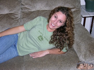 Smoking hot brunette with curly hair takes off her green shirt and pose her stunning body in black bra and jeans before she gets naked and expose her lusty boobs and indulging twat on a brown bed and wooden drawer. - XXXonXXX - Pic 2