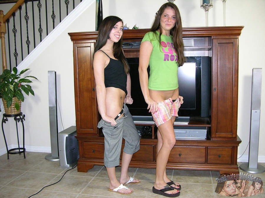 Young babe in black shirt and gray shorts and a teen chick wearing green shirt and vari-colored shorts pose their skinny bodies then teases with their sweet asses and lusty pussies before they strip off their clothes and reveals their petite boobs as they lay naked on a gray bed. - XXXonXXX - Pic 3