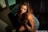 Asian brunette sits on a black couch and seduces with her alluring body