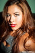 Asian brunette sits on a black couch and seduces with her alluring body
