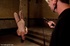 In a shadowy room, a brunette is bound and suspended as she succumbs to