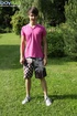 Cute guy wearing pink shirt has fun in the backyard and poses doggy style