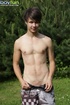 Cute guy wearing pink shirt has fun in the backyard and poses doggy style