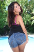 Sweet chick peels off her black shirt and jeans shorts by a pool then